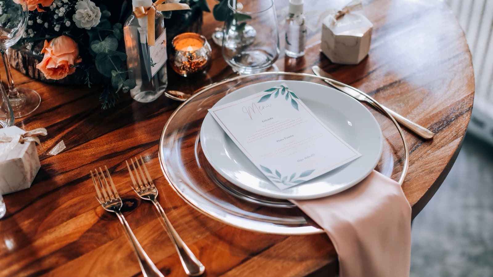 Wedding reception table with a menu card on the plate, linen napkin and flowers